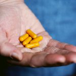 yellow medication pill on persons hand