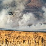 A helicopter is flying over a large cliff